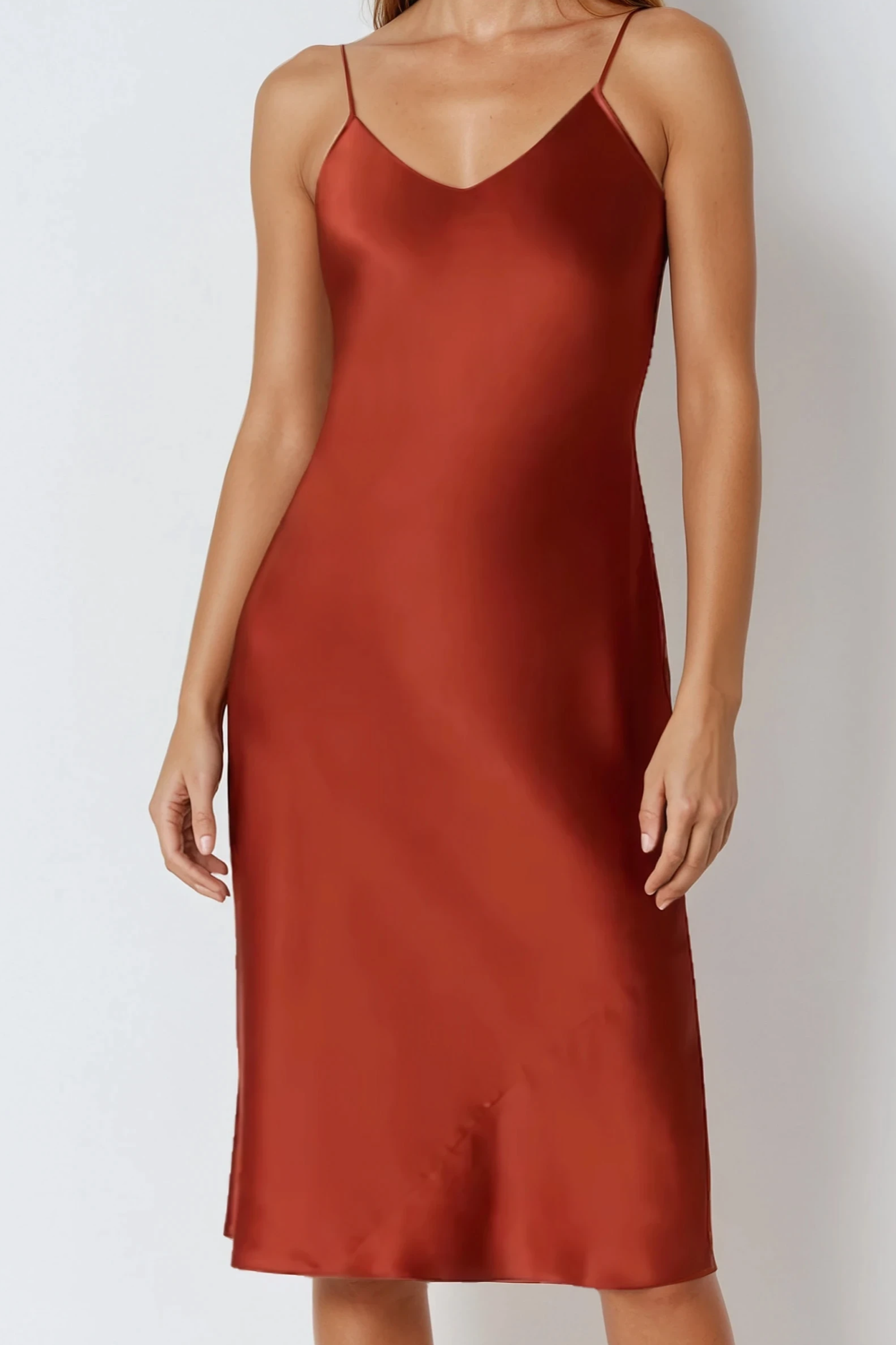 Rust-colored silk satin slip dress worn by a model on a white background