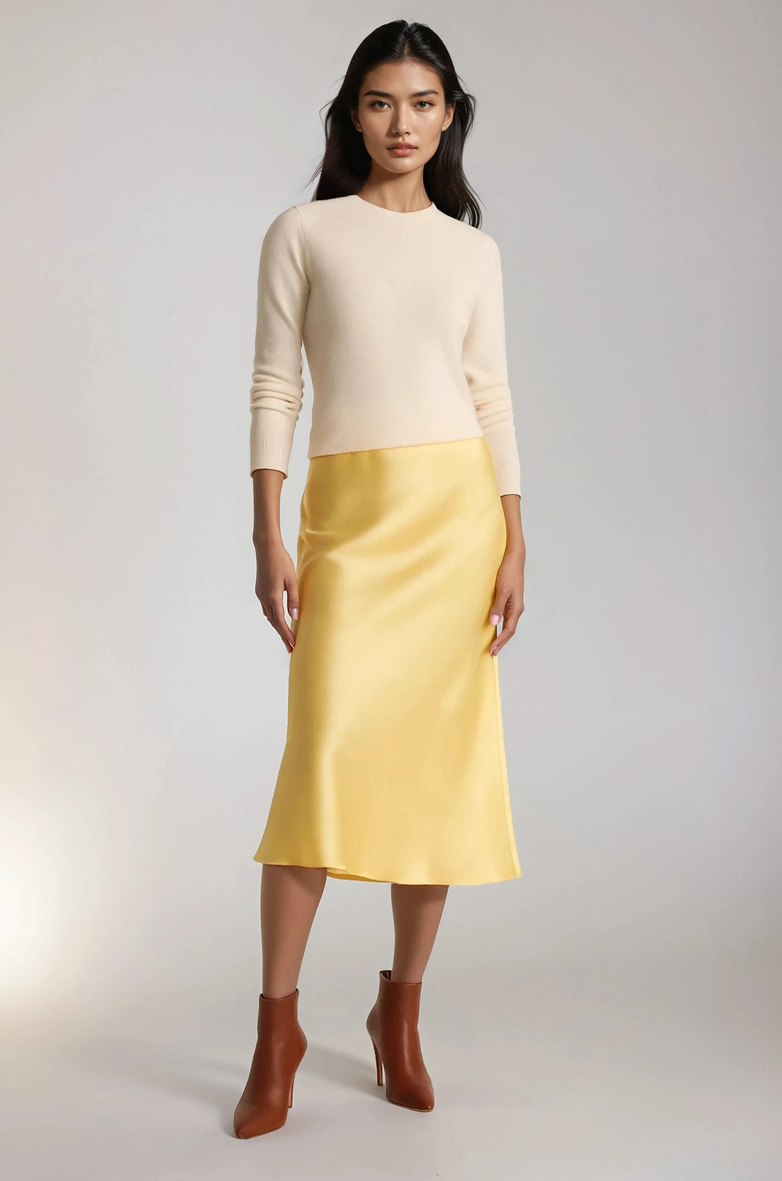 Woman wearing a cream sweater and yellow silk skirt on a white background