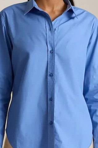 close-up of a blue button-up shirt on a neutral background
