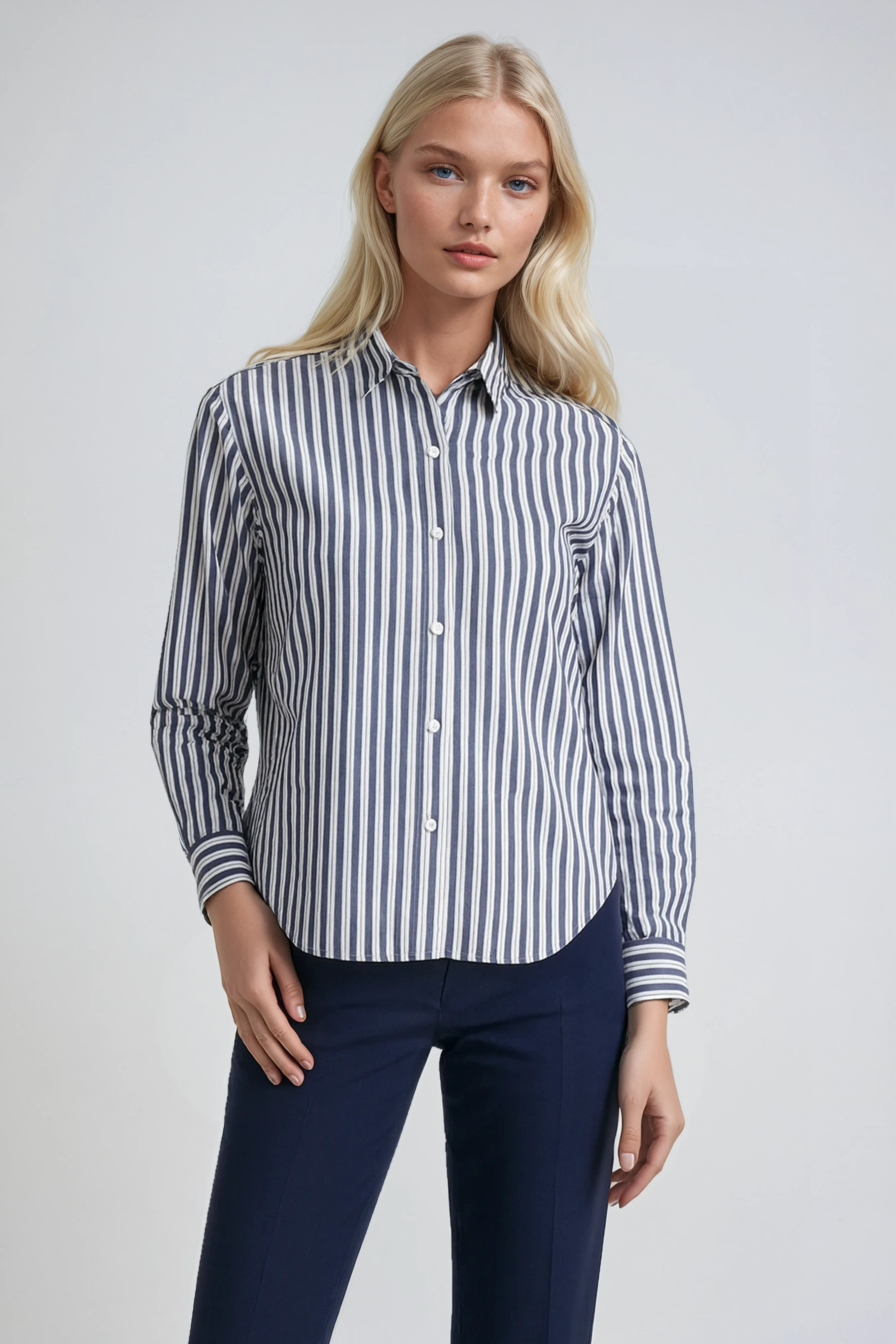 Woman wearing a striped organic cotton shirt and dark pants on a plain background