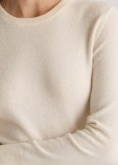 Close-up of a person wearing a cream long-sleeve shirt.