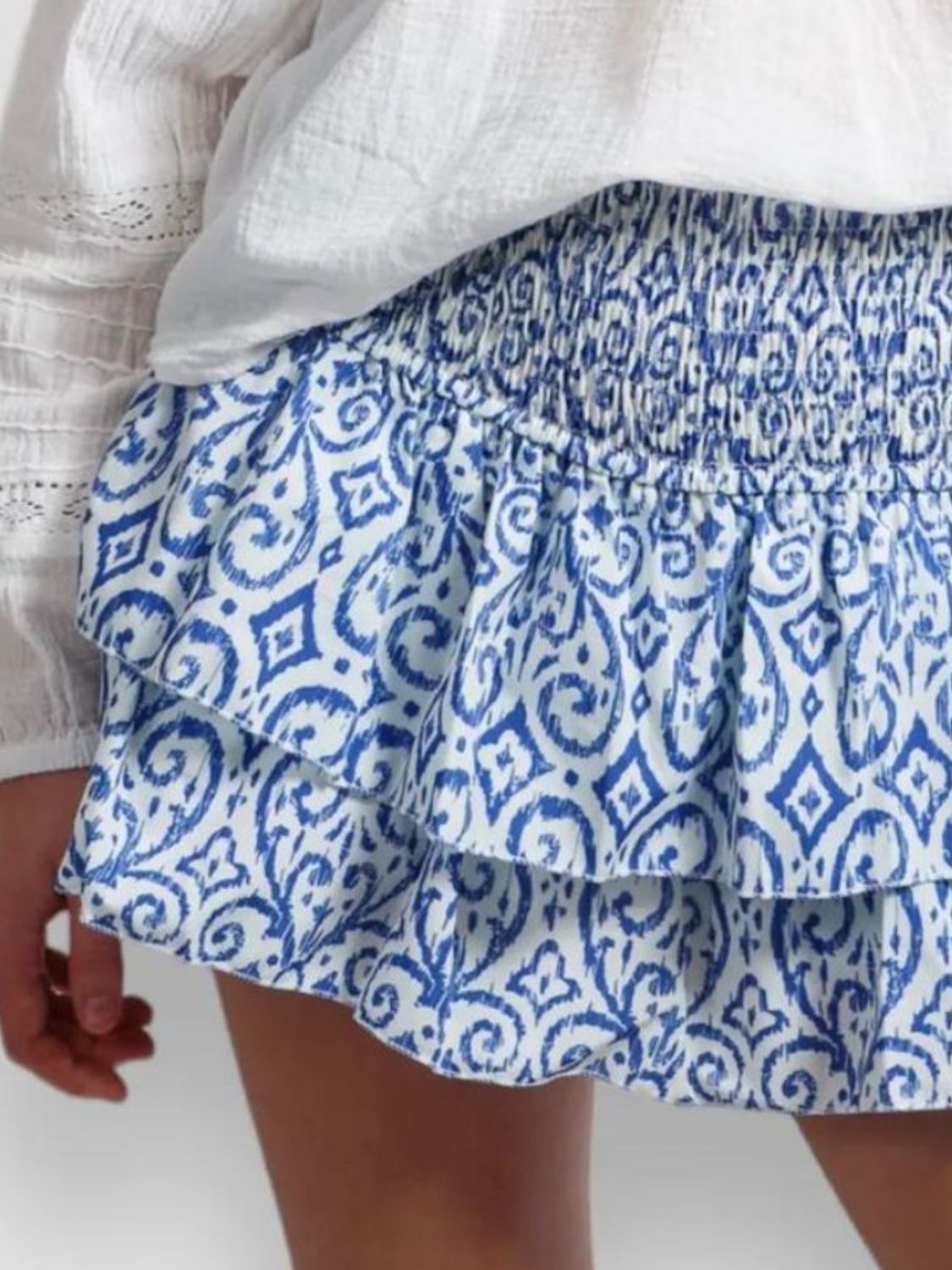 model wearing blue and white patterned layered mini skirt worn with a white top on a plain background