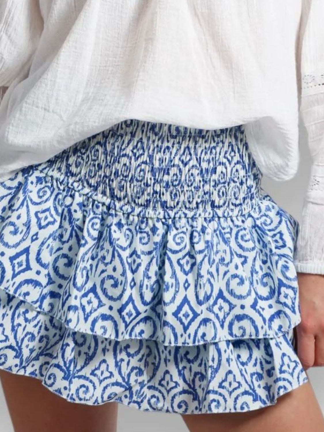 Model wearing blue and white layered mini skirt with white top on a neutral background