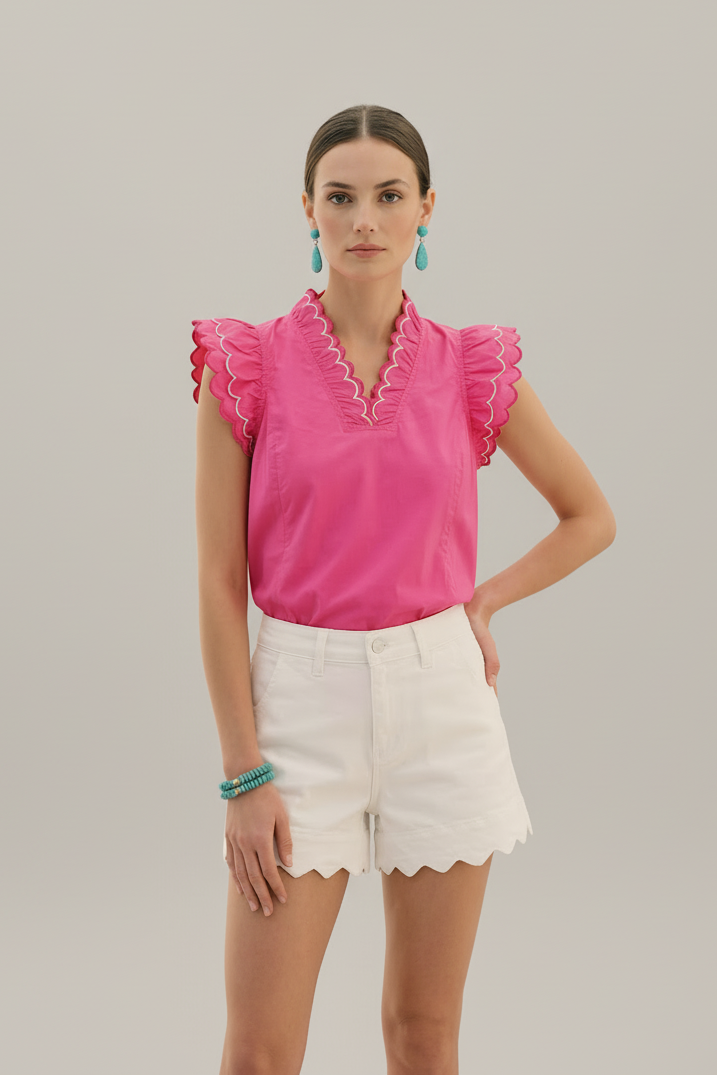 Woman wearing a pink blouse with ruffled sleeves and white shorts in a professional studio