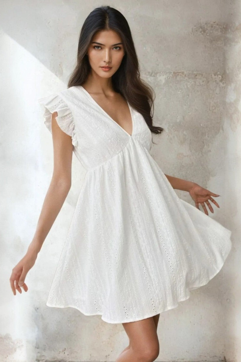 Woman wearing a 100% Cotton White Eyelet Mini Dress with Ruffled Sleeves against a neutral background. Women's dress, mini dress, cotton dress