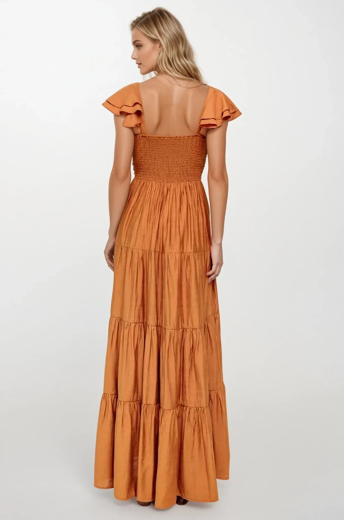 Woman wearing a rust colored dress with ruffled sleeves on a white background. Women's dresses, maxi dress, fall dress, rust colors
