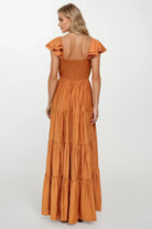 Woman wearing a rust colored dress with ruffled sleeves on a white background. Women's dresses, maxi dress, fall dress, rust colors