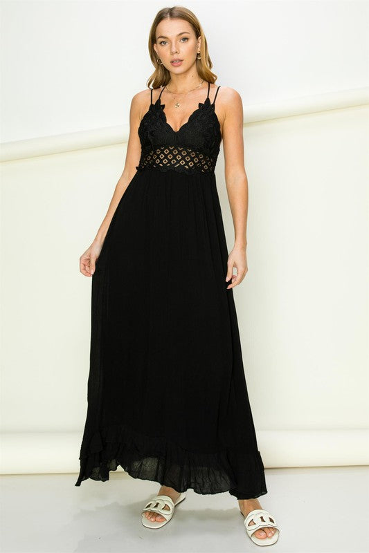 Woman wearing a black dress with lace detailing against a white background. Women's dress, maxi dress