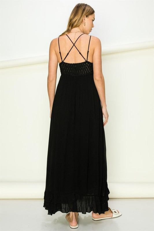 Woman wearing a black dress with thin straps and embellishments on a white background. Women's dress, maxi dress
