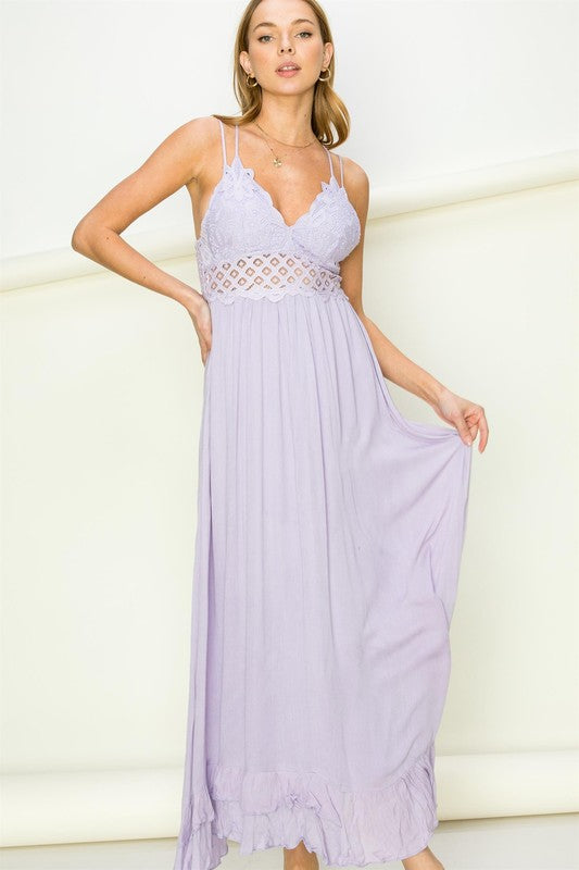 Woman wearing a lavender maxi dress with a white lace overlay against a white background. Women's dress, maxi dress