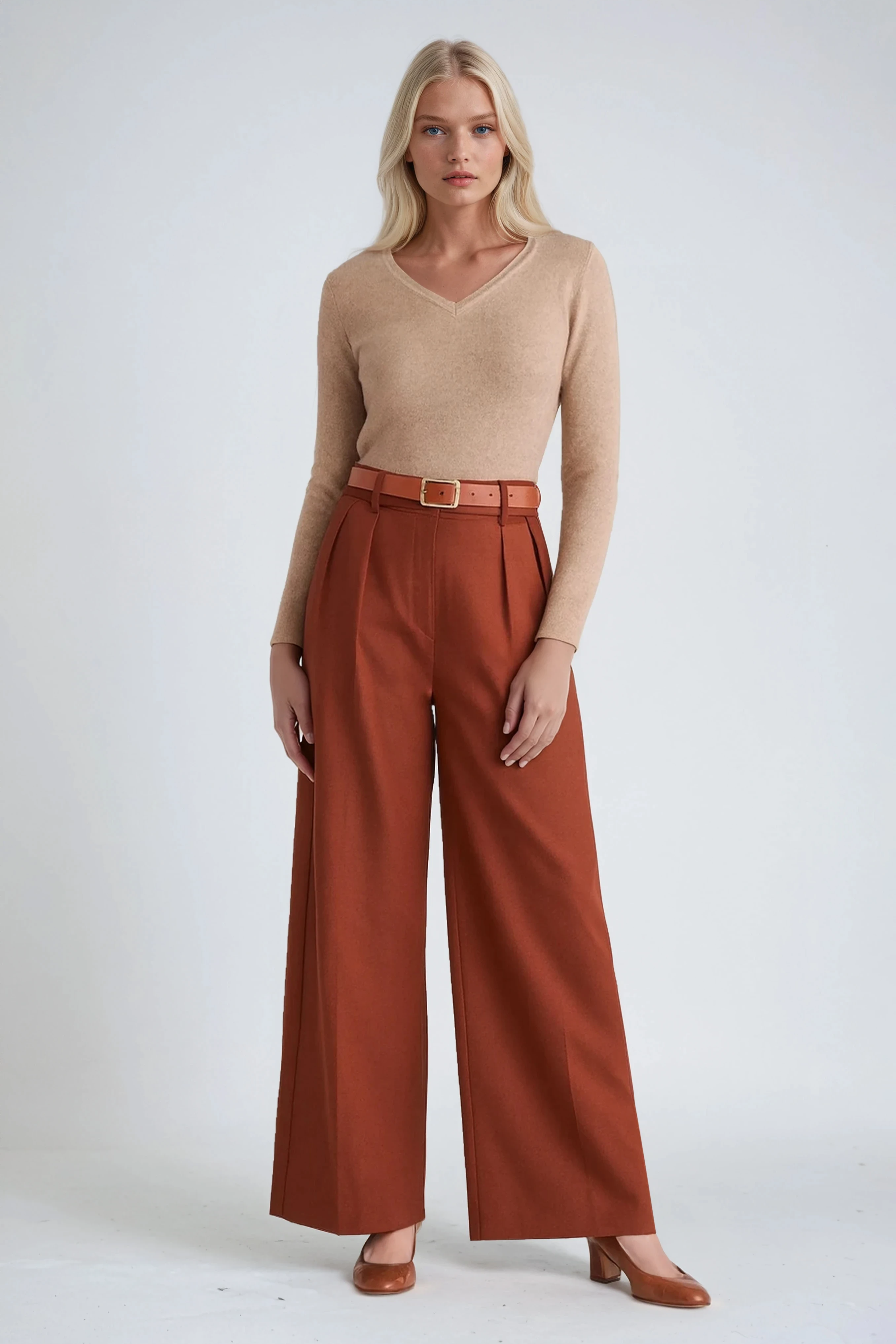 Woman wearing a beige sweater and rust-colored wide-leg pants on a white background