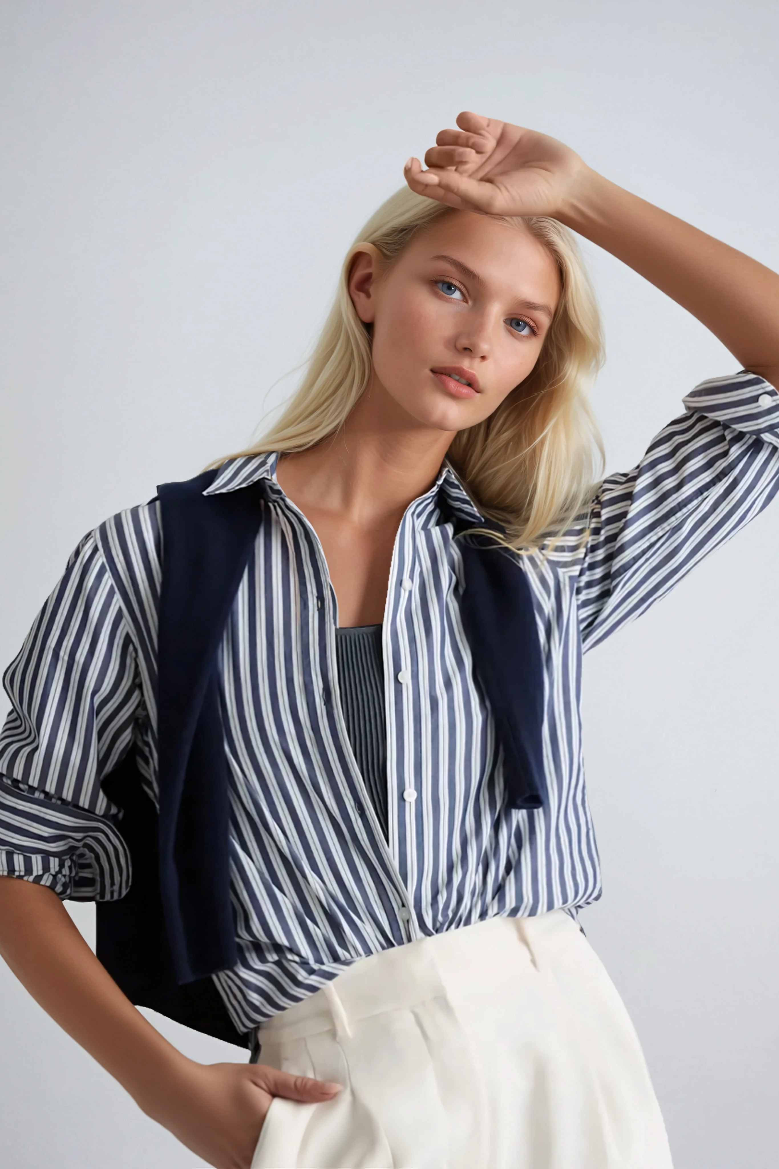 Woman wearing a striped organic cotton poplin shirt and white pants against a plain background