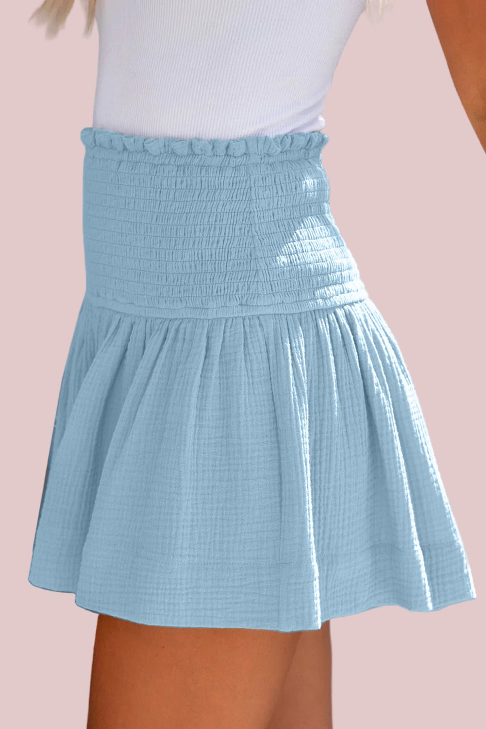 100% Cotton Pastel Blue Smocked Shorts worn by a person on a pink background