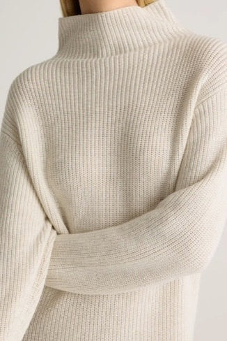 Close-up of a beige ribbed sweater on a plain background