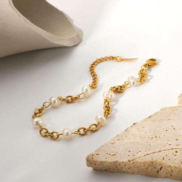 Gold chain necklace with pearls on a light background
