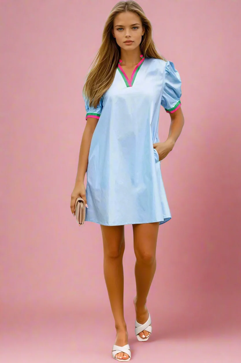 Woman wearing a l00% Cotton Light Blue Mini Dress with Stripe Detail against a pink background. Women's dresses, cotton dresses, mini dress