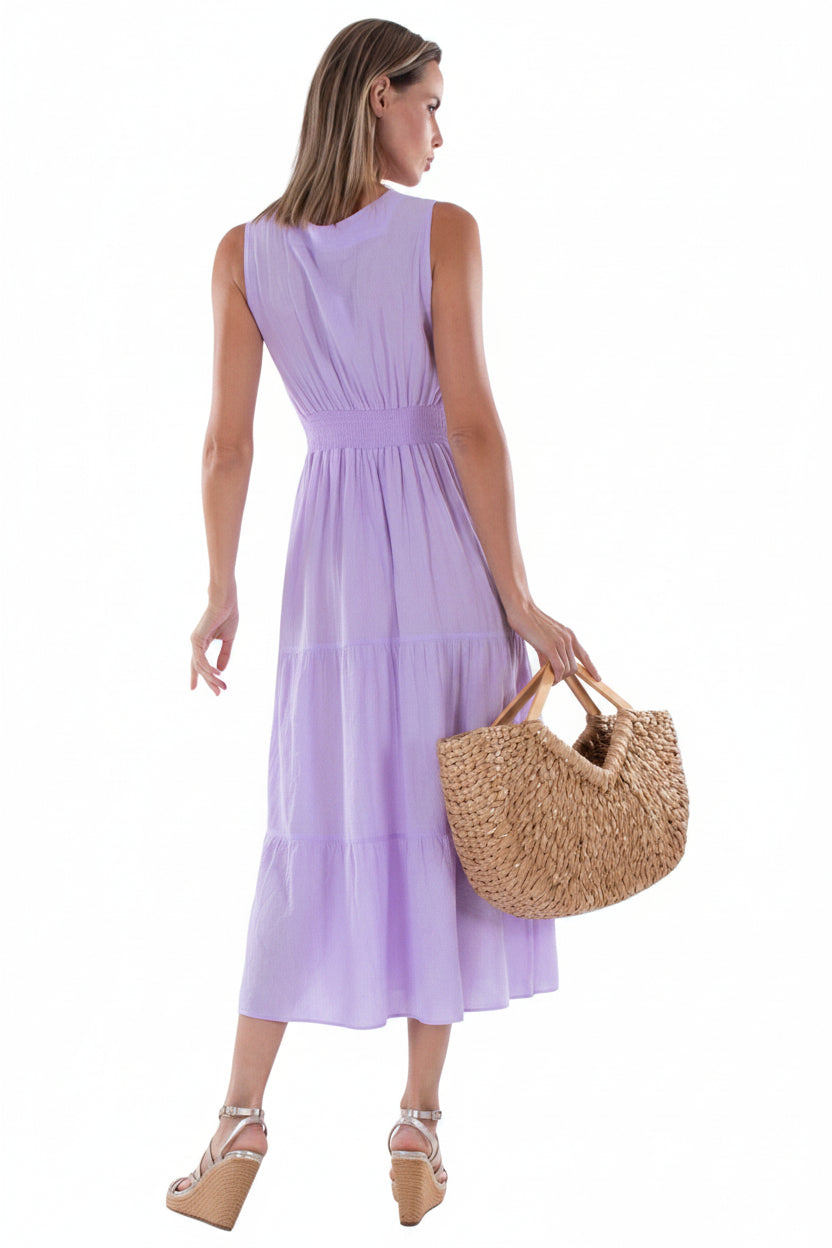 Woman wearing a lilac dress holding a straw bag on a white background