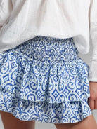 Model wearing blue and white layered mini skirt with white top on a neutral background