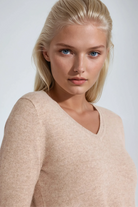 Woman wearing a beige sweater against a plain background